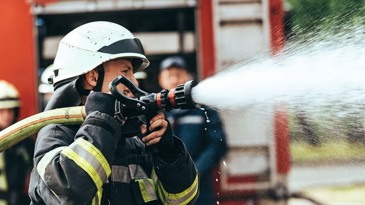 Firefighter holding active fire hose