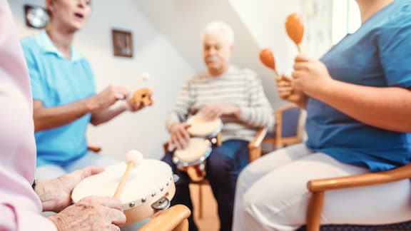 Care home residents playing musical instruments sitting in circle