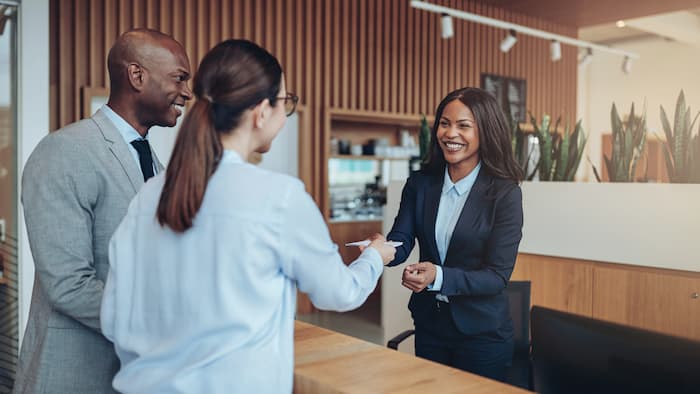 Business conversation in a hotel lobby including a female receptionist, a business man and woman