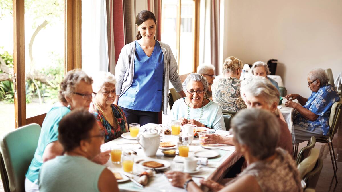 A group of senior citizens sits at a table eating cake