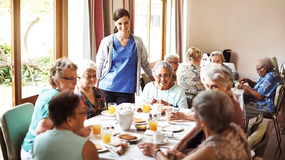 Care Home worker with residents around table