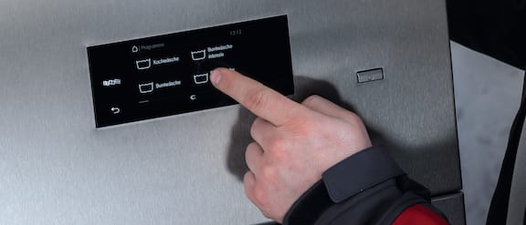 Fingeren betjener touch-displayet på en Benchmark-maskine