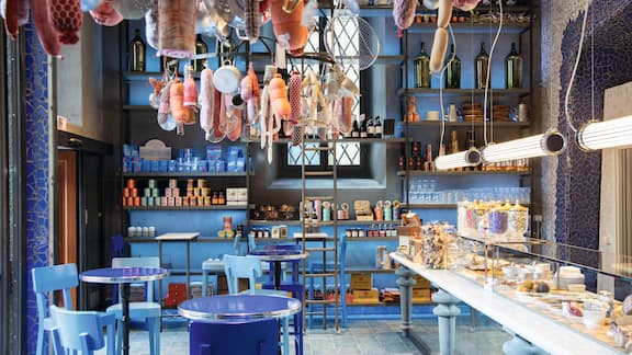 View of hotel restaurant with blue design, sausages and kitchen utensils hanging from the ceiling.  