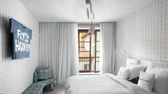 Paradiso hotelkamer met een bed in het midden, overwegend in het wit.