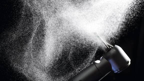 Dental drill spraying water against black backdrop