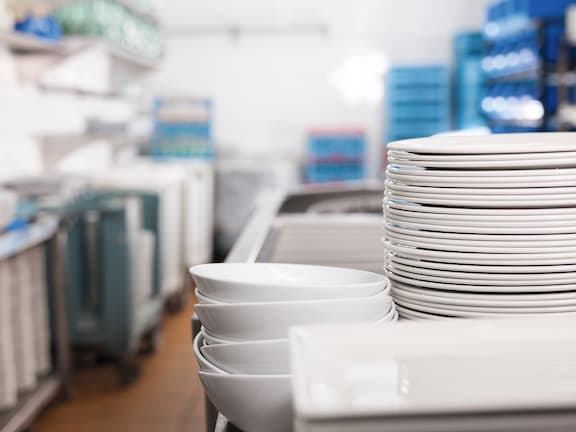 Kitchen assistant washes up used dishes in a hospital kitchen