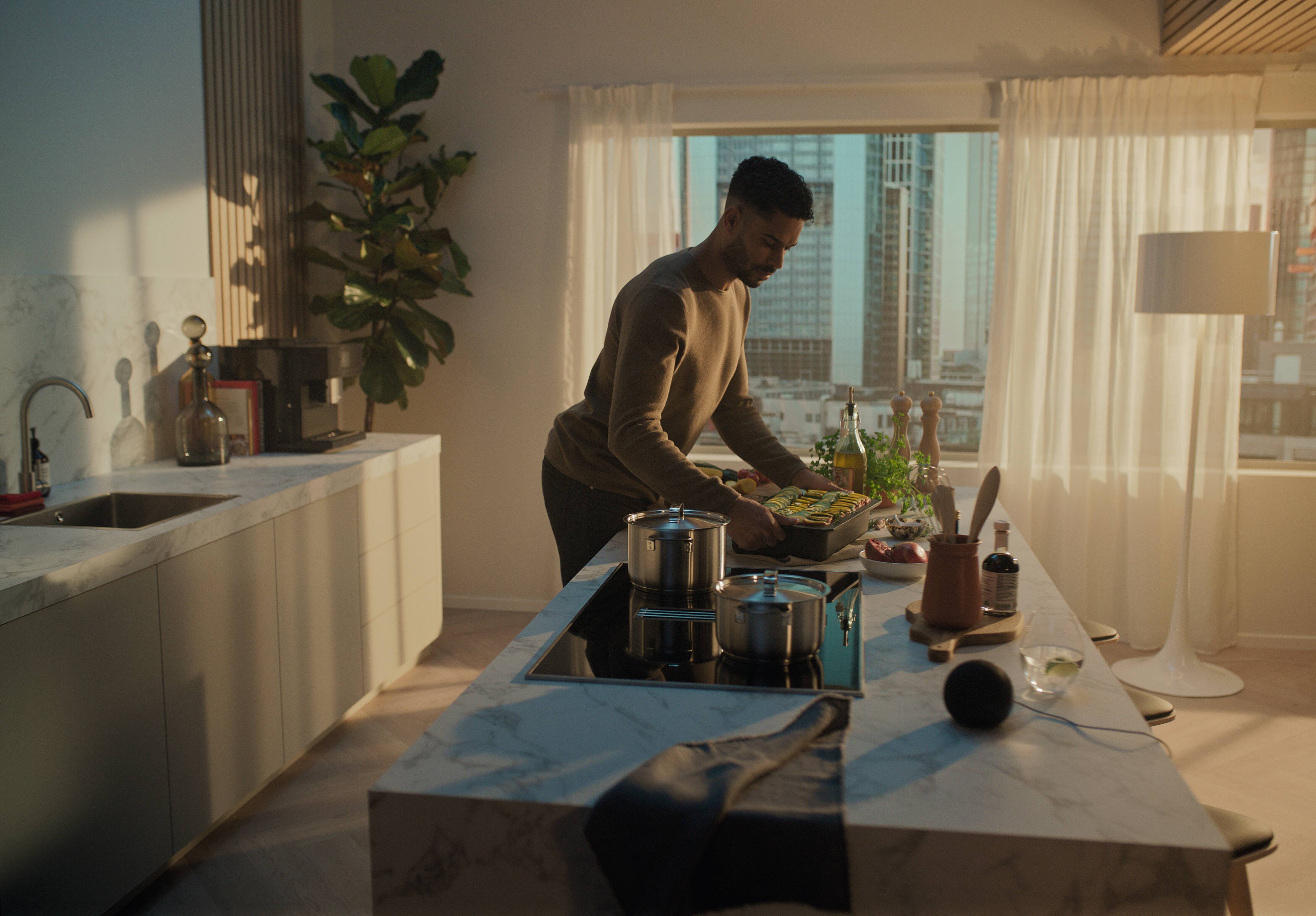 man cooking on a Miele hob with a voice assistant device nearby man cooking on a Miele hob with a voice assistant device nearby