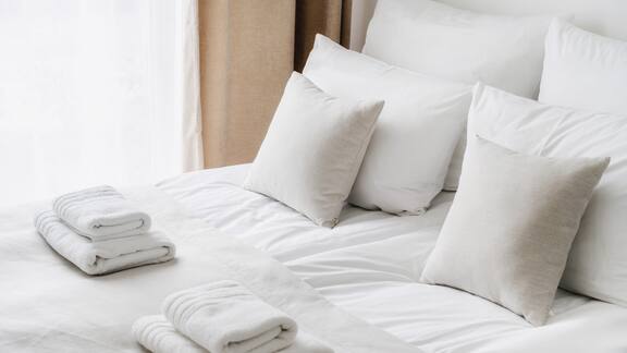 Ein Hotelbett mit weißen Laken und gefalteten Handtüchern darauf