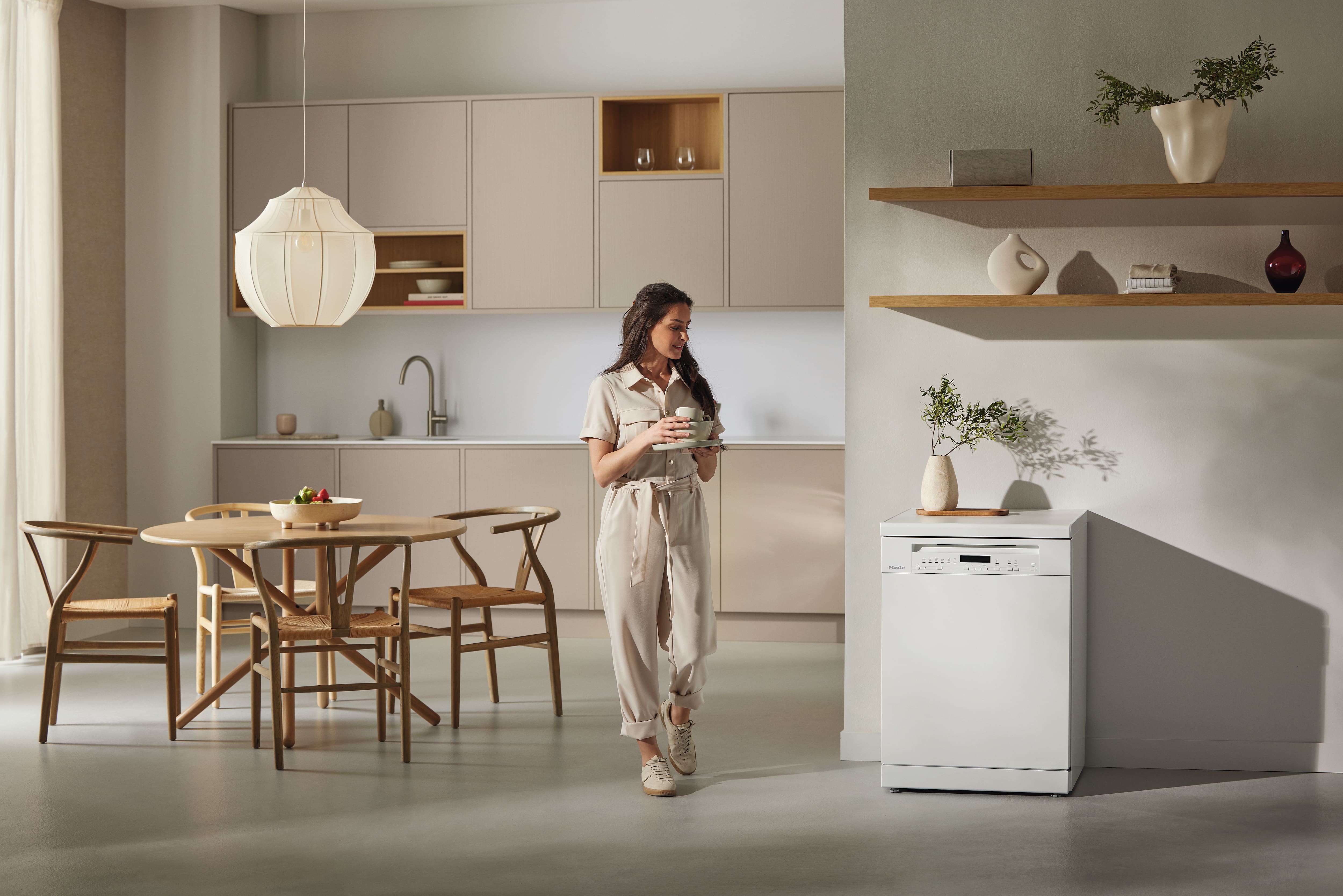 Modern and clean kitchen setting with a person passing next to a Miele freestanding dishwasher Modern and clean kitchen setting with a person passing next to a Miele freestanding dishwasher