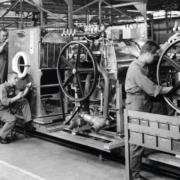 A historical photo showing the assembly of Miele Professional washing machines