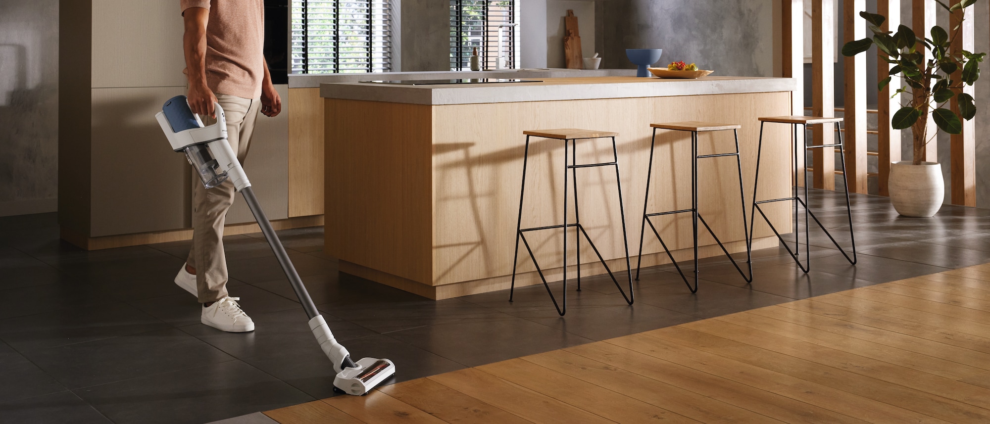 a man using a Miele cordless stick vacuum cleaner