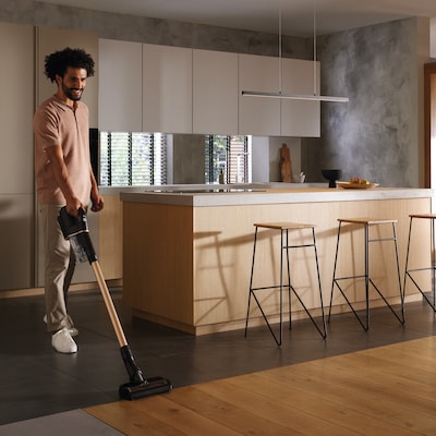Image of a person using a cordless stick vacuum cleaner