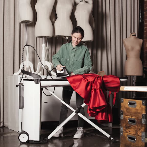 A laundry room worker is using the Miele flat ironer PRI 214.