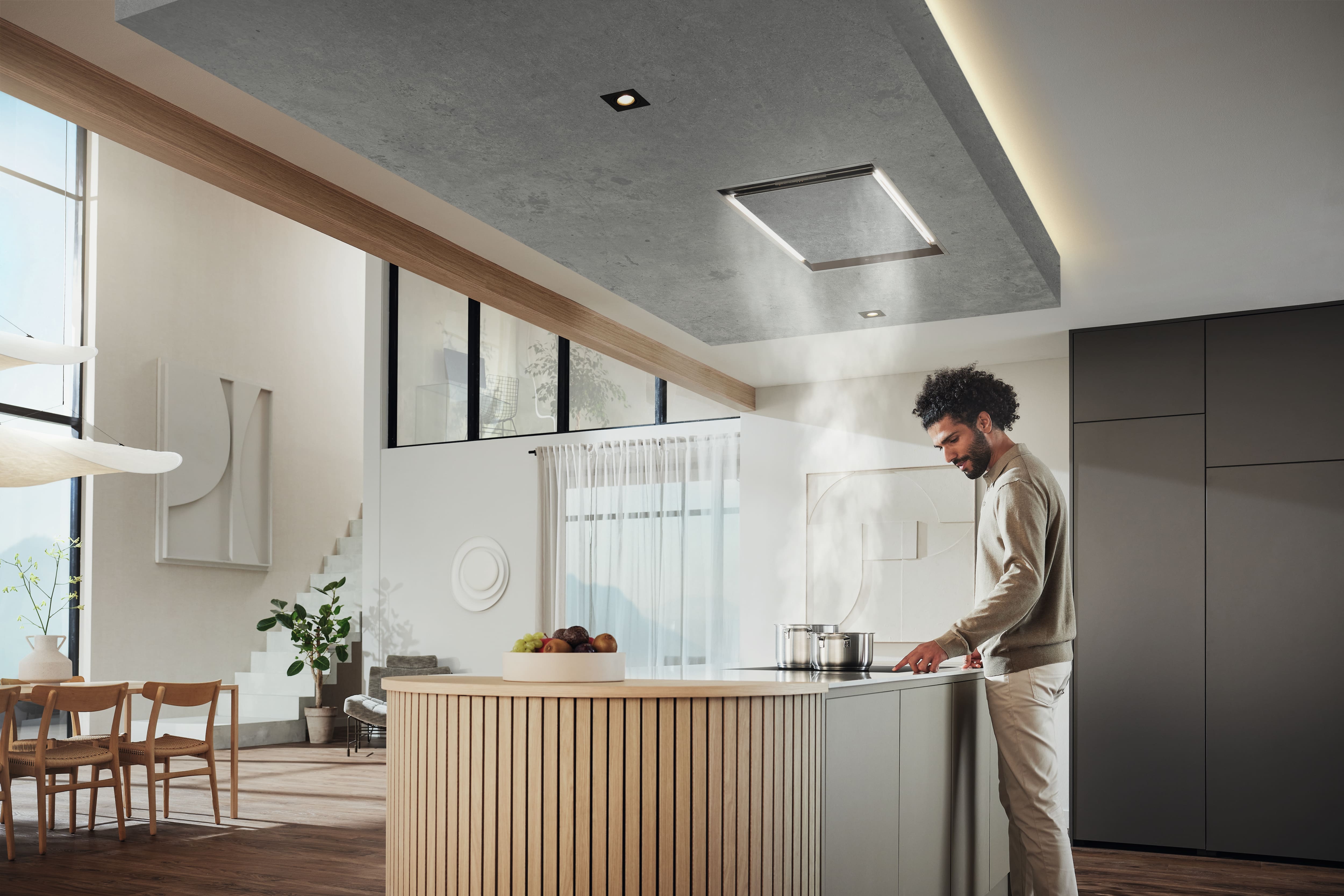 A modern and wide kitchen setting with a person cooking over the hob