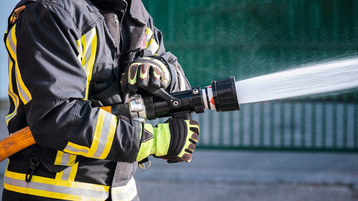 Firefighter holding active fire hose