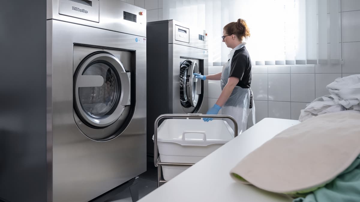 Pracownik domu opieki ładuje pralnicę Miele Professional