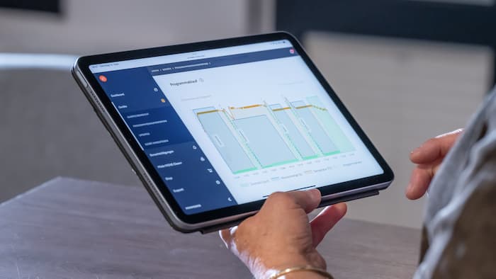 Jemand hält ein Tablet, das eine visuelle Darstellung eines Programmablaufs anzeigt.