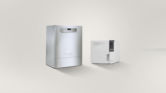 Una lavadora desinfectadora integrada junto a un autoclave de sobremesa Cube ante un fondo gris.
