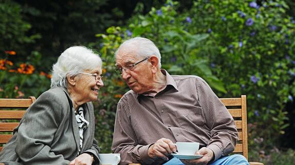 Et eldre par sitter på en hagebenk