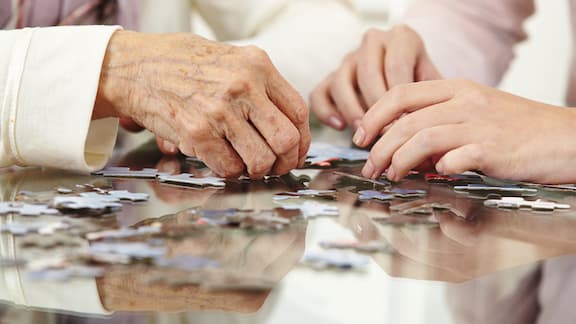Les mains de personnes âgées résolvent des puzzles