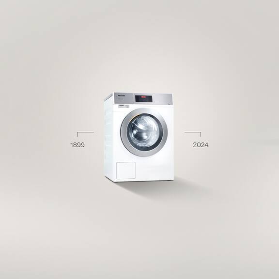 Een Kleine Geweldenaars Performance Plus wasmachine staat tegen een grijze achtergrond