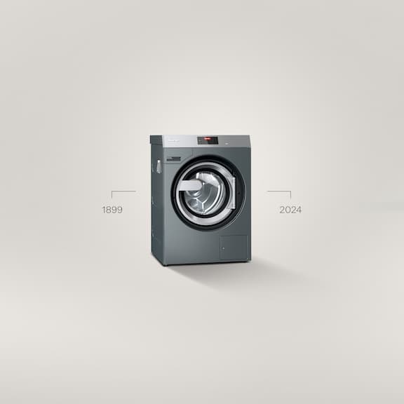 A PWM 509 Performance Benchmark washing machine stands in front of a grey background