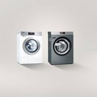 Een Kleine Reuzen wasmachine staat links van een Benchmark-wasmachine tegen een grijze achtergrond