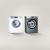 Eine Kleine Riesen Waschmaschine steht links neben einer Benchmark Waschmaschine vor einem grauen Hintergrund