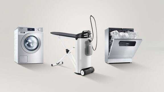 From left to right, a Little Giant Performance washing machine, a PIB 100 steam ironing system and a half-open MasterLine fresh water dishwasher stand next to one another in front of a grey background