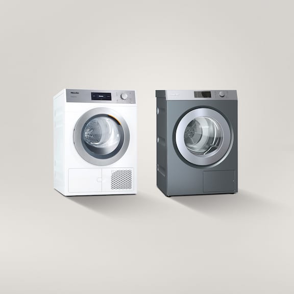 Two tumble dryers next to each other on a grey background