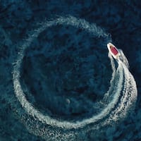 Ein Boot gleitet auf dem Meer im Kreis, von oben gesehen