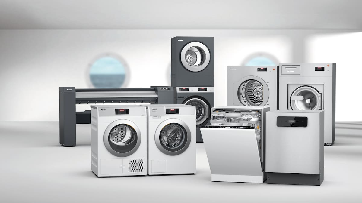 Washing machines, tumble dryers and an ironer on a grey background with a porthole