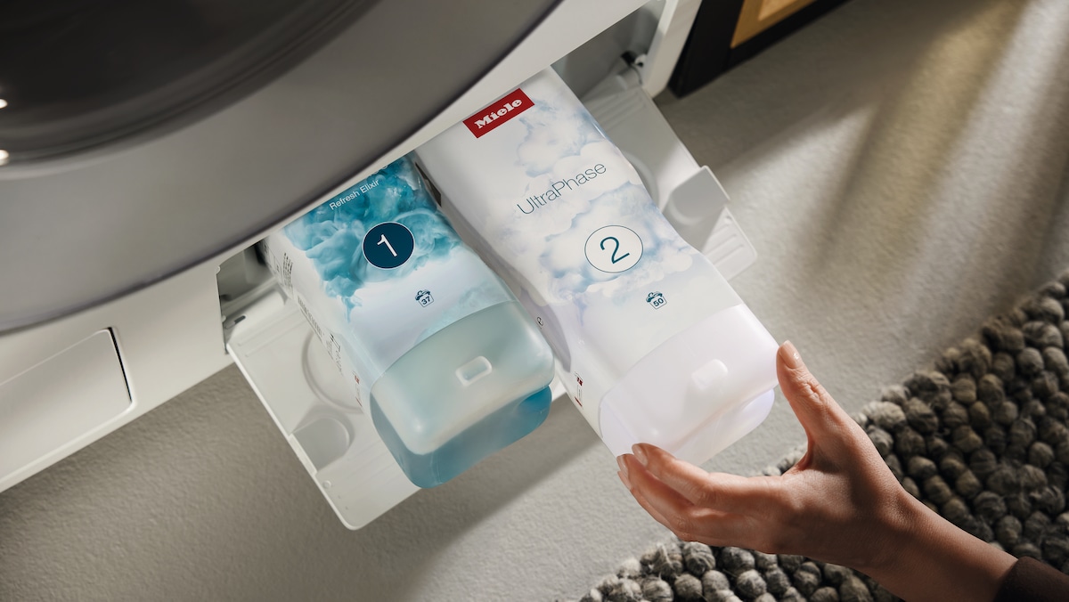 hand putting in a Miele washing machine the second bottle of UltraPhase