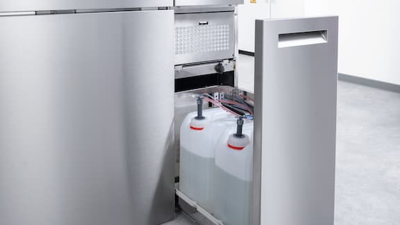 Dwa kanistry ze środkiem czyszczącym są umieszczone w dodatkowej szufladzie do przechowywania myjni laboratoryjnej PLW 8636 i podłączone do pomp dozujących.
