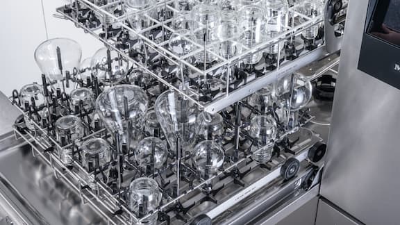 Otwarta myjnia laboratoryjna PLW 8636 z czterema różnymi modułami EasyLoad wyposażona w różne rodzaje szkła laboratoryjnego, takie jak kolby stożkowe i kolby okrągłe w różnych rozmiarach.