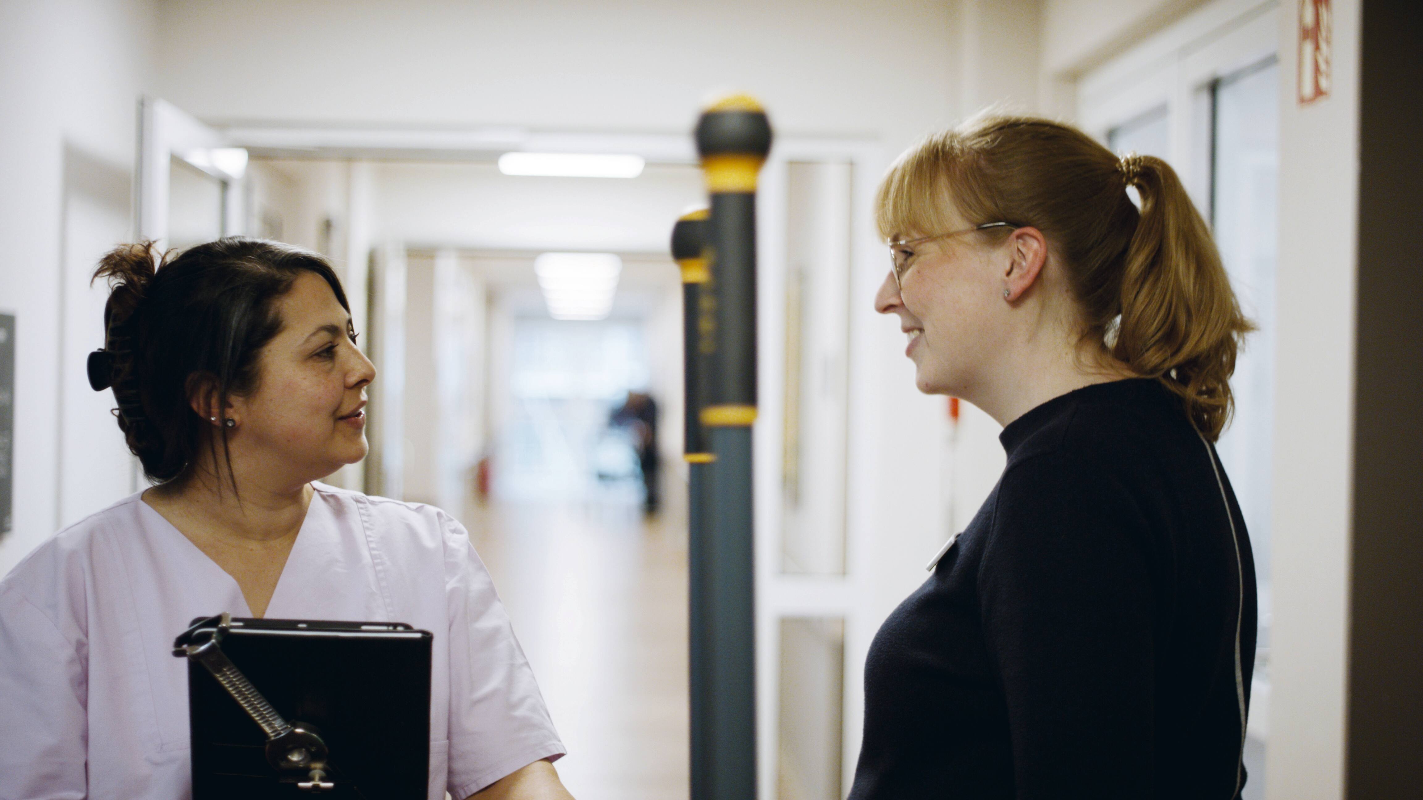 Une agente d’entretien et la direction de l’intendance discutent dans le couloir d’un établissement de soins.