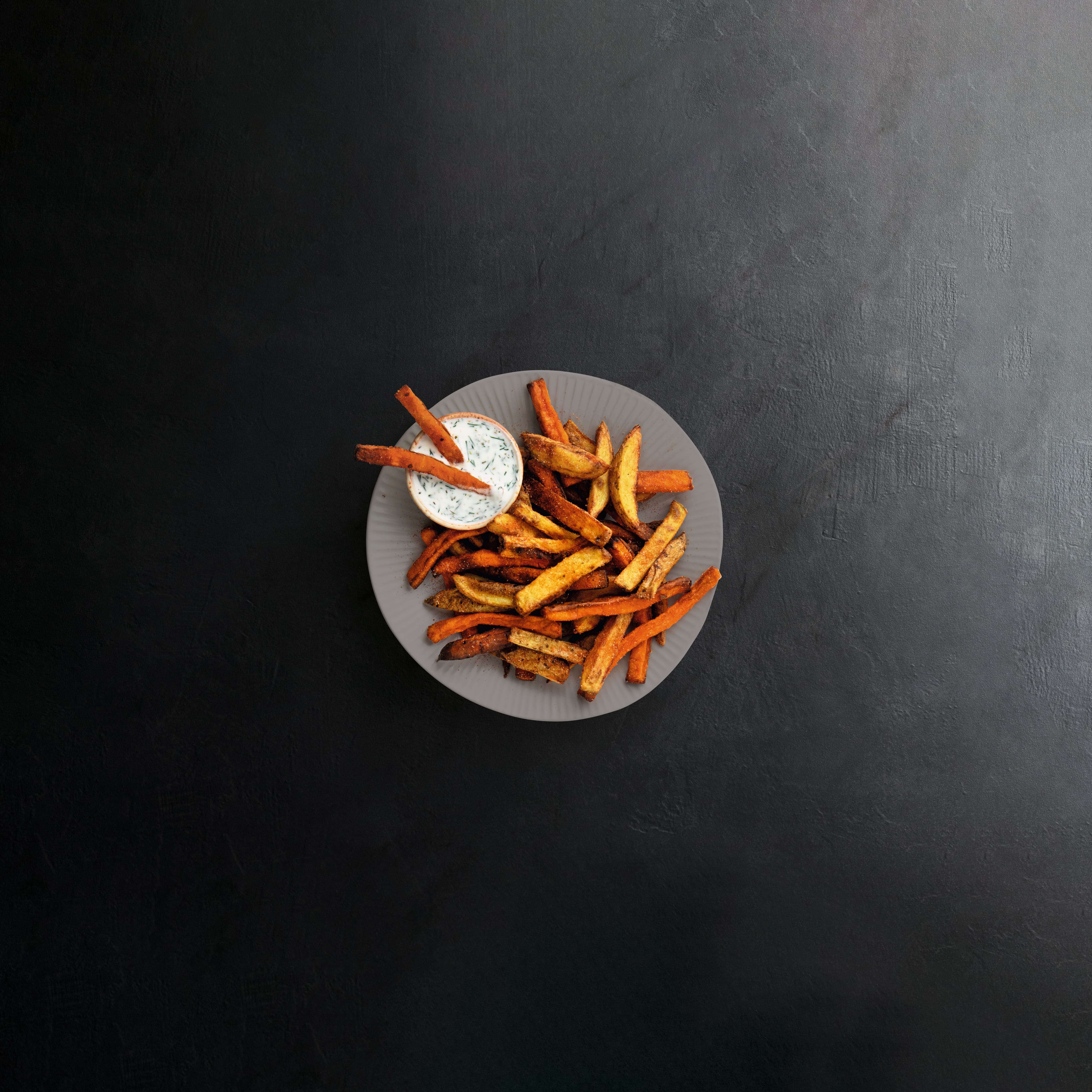 A plate of fries with sauce on the side