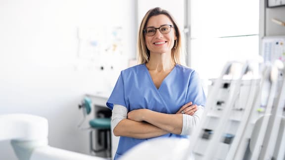 A female dentist smiles at camera in dental practice