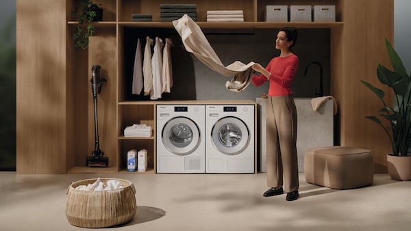 woman folding cloths in a laundry room with Miele appliances