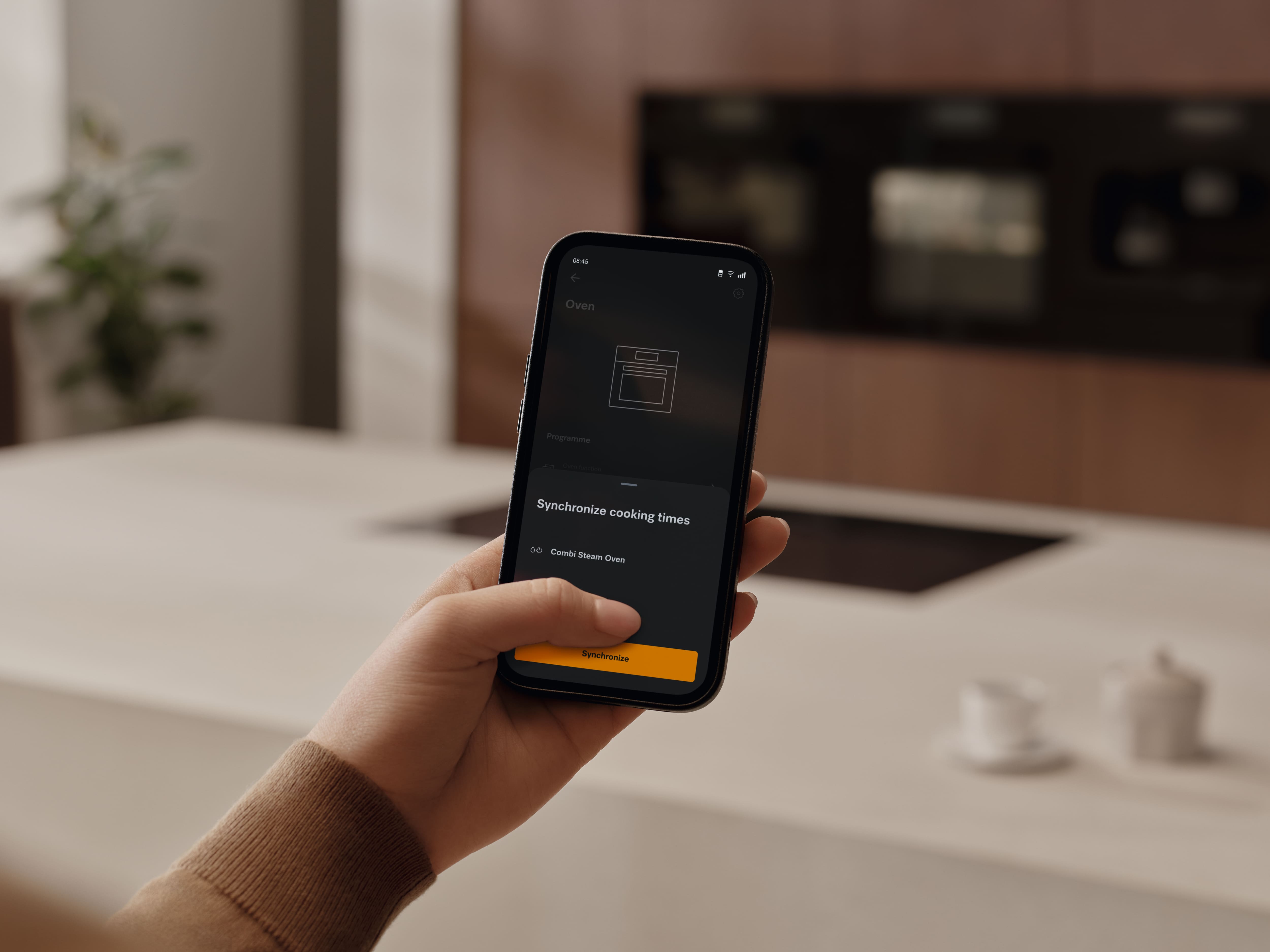 A person holding a smartphone with the MieleApp open