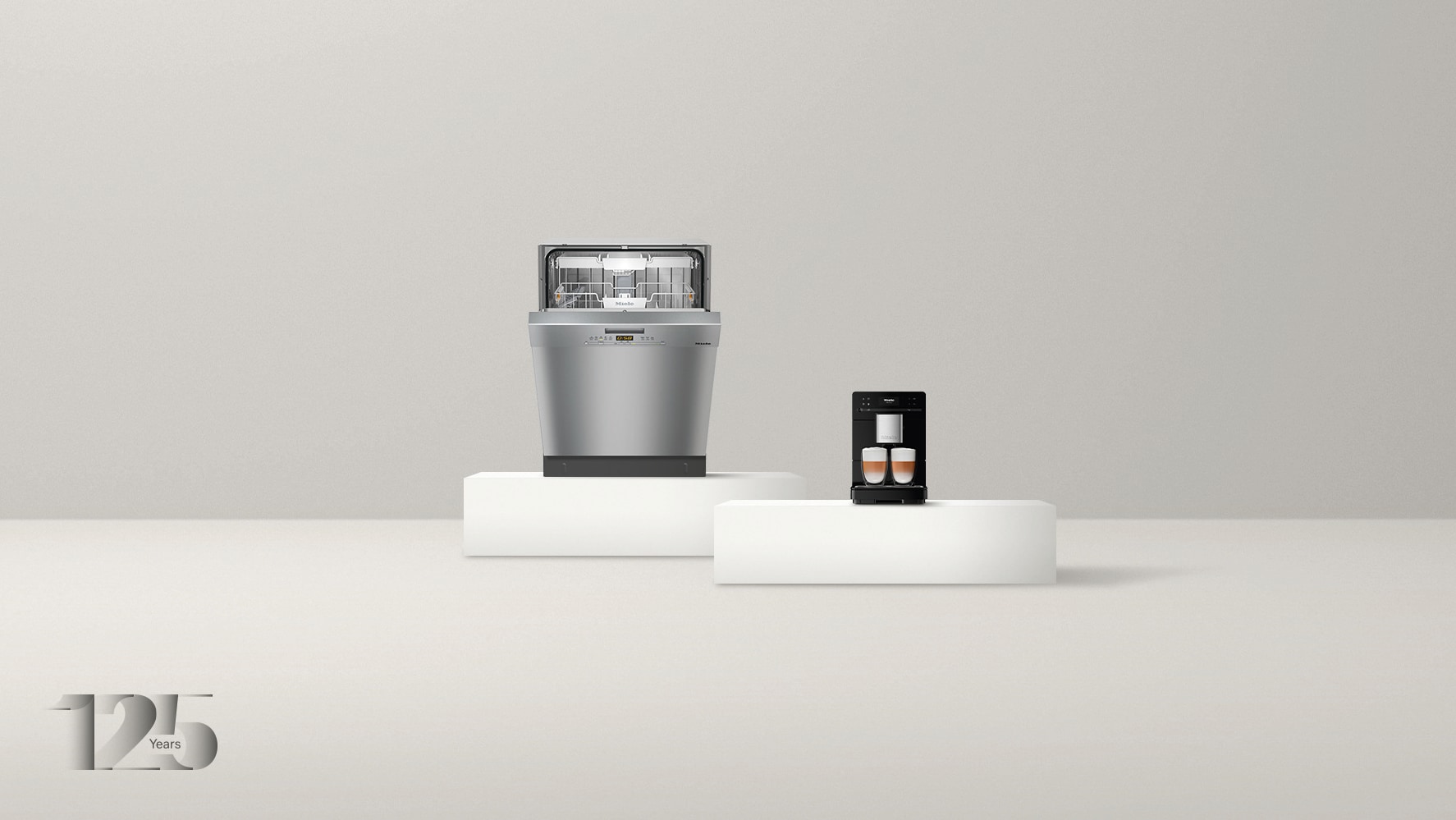 Dishwasher and countertop coffee machine on pedestals with a grey background