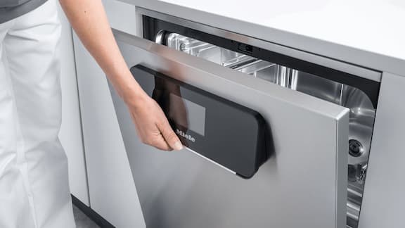 A hand opens the glass door of an ExpertLine thermal disinfector