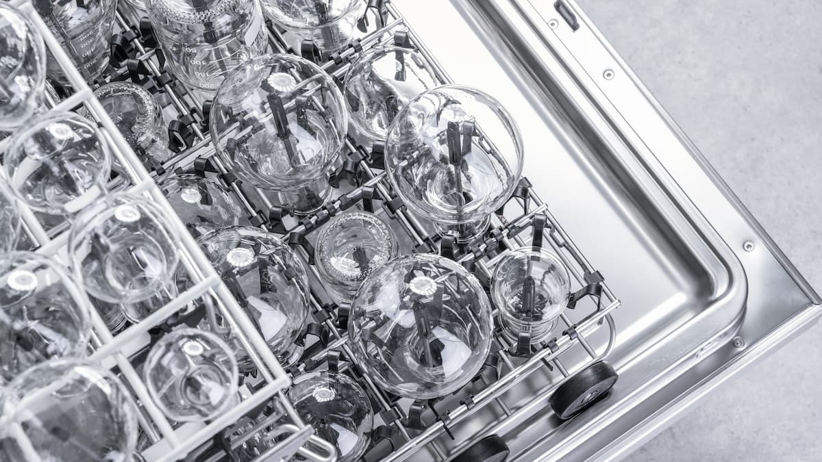 Open undercounter laboratory washer loaded with EasyLoad inserts and laboratory glassware.