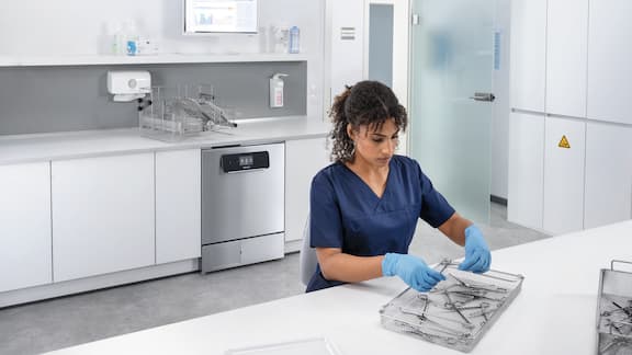 A medical assistant loads the ExpertLine washer disinfector in medical reprocessing room