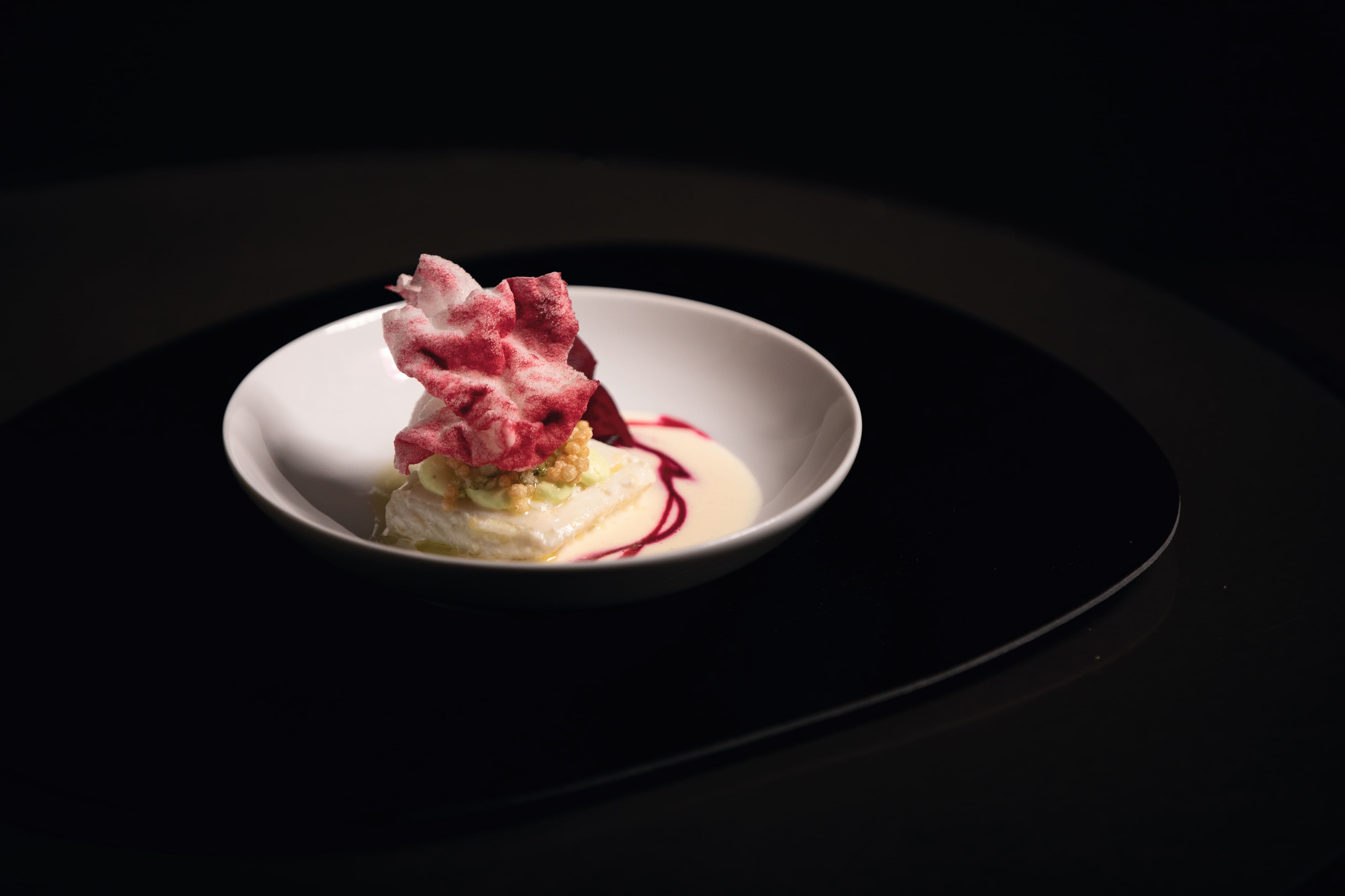 Elegancki deser fine dining podany na głębokim talerzu sfotografowany na ciemnym tle Elegancki deser fine dining podany na głębokim talerzu sfotografowany na ciemnym tle