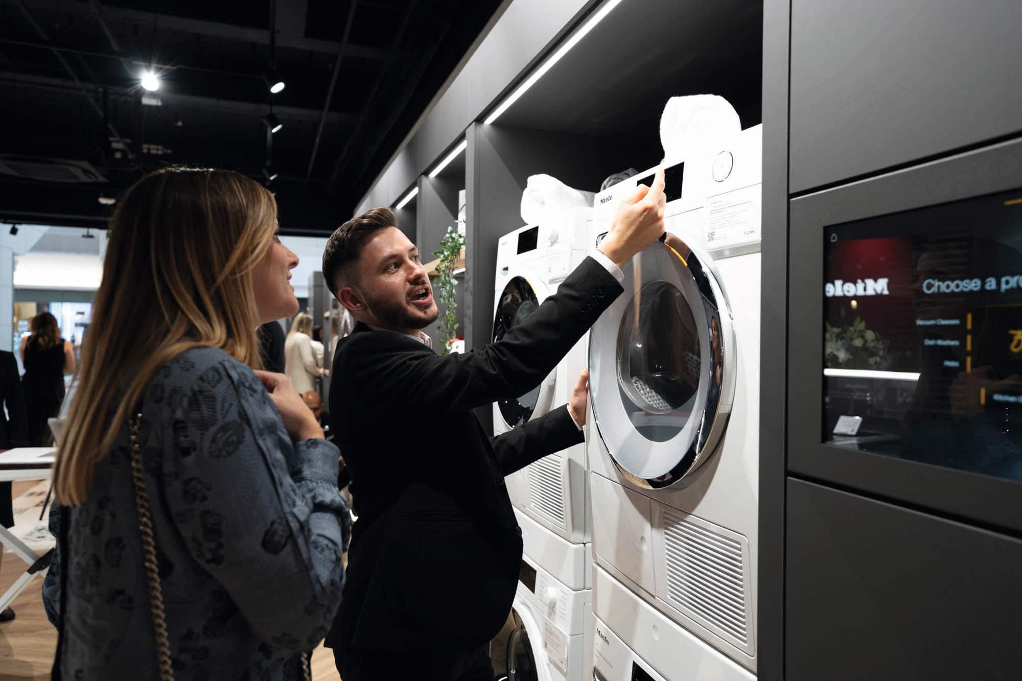 Doradca prezentujący klientce panel sterujący pralki Miele w salonie Miele Experience Center