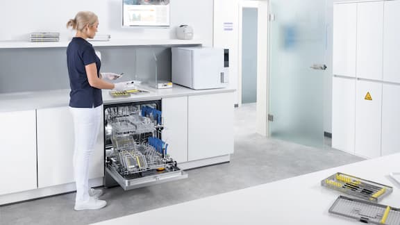 Asystentka stomatologiczna pracuje w pomieszczeniu do reprocesowania narzędzi z urządzeniem ExpertLine.