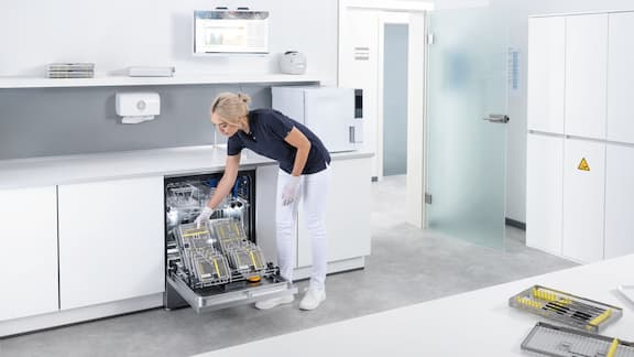 Asystentka stomatologiczna ładuje myjnię-dezynfektor Miele Professional narzędziami stomatologicznymi do reprocesowania