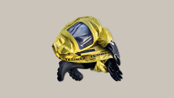 A yellow chemical protection suit on a plain grey background