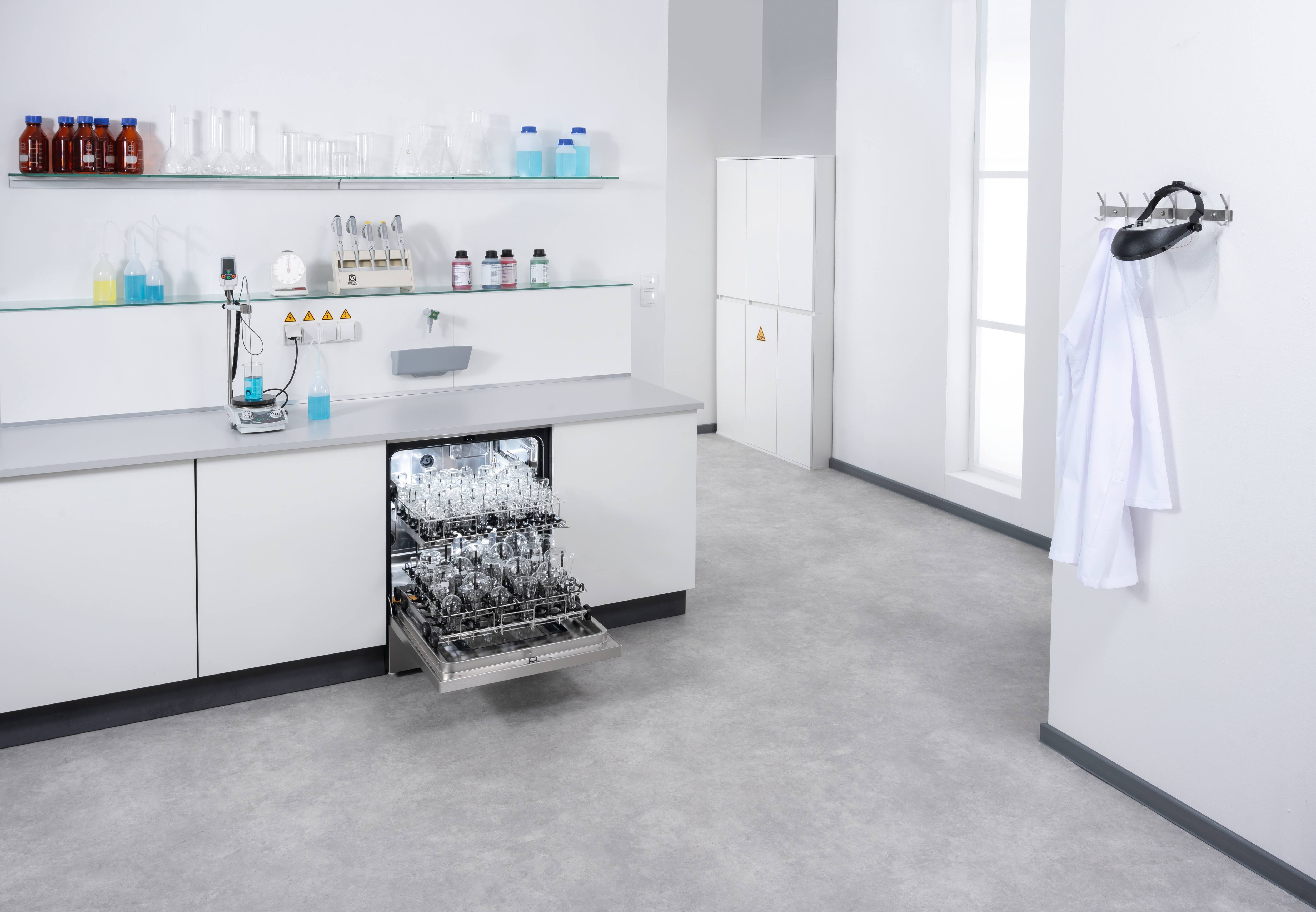 Ein geöffneter ExpertLine Laborspüler ist in einer Laborzeile eingebaut und mit EasyLoad Modulen und verschiedenem Laborglas bestückt,